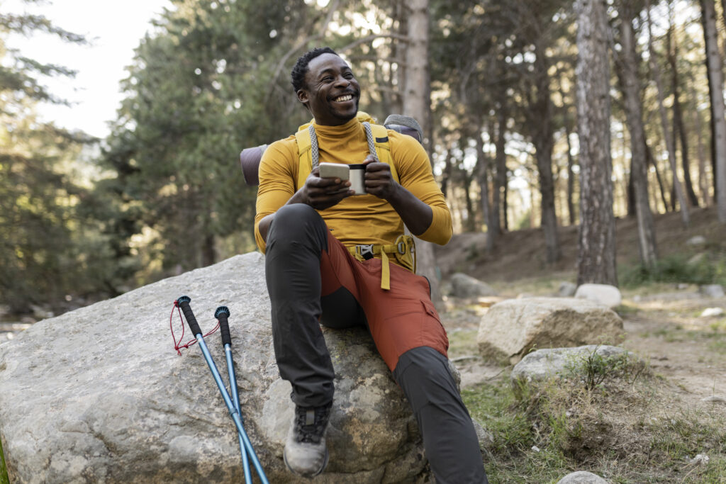 Black hiker wearing Outdoor Afro Designs performance hiking pants while relaxing on a rock during a forest trail adventure
