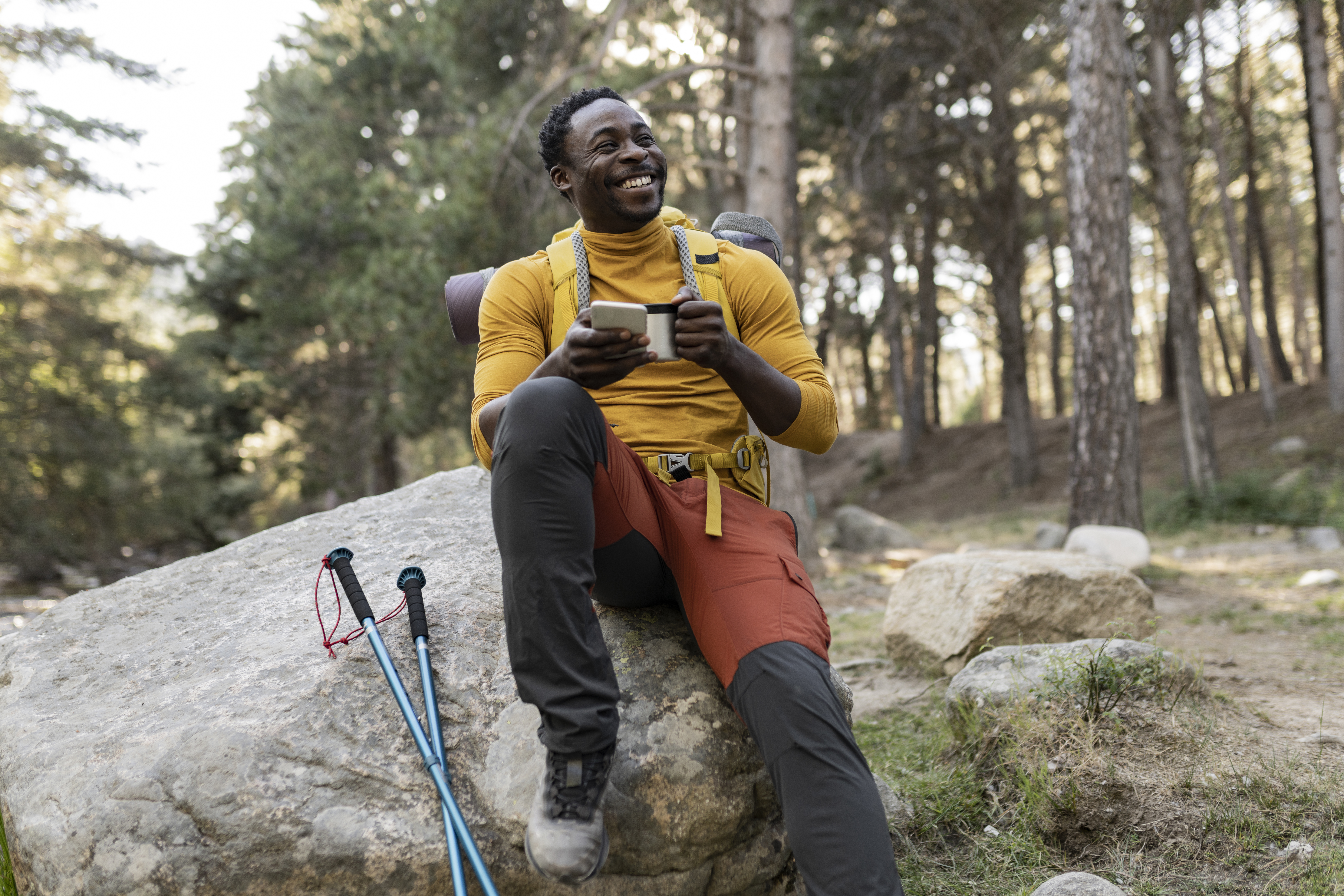 Black hiker wearing Outdoor Afro Designs performance hiking pants while relaxing on a rock during a forest trail adventure