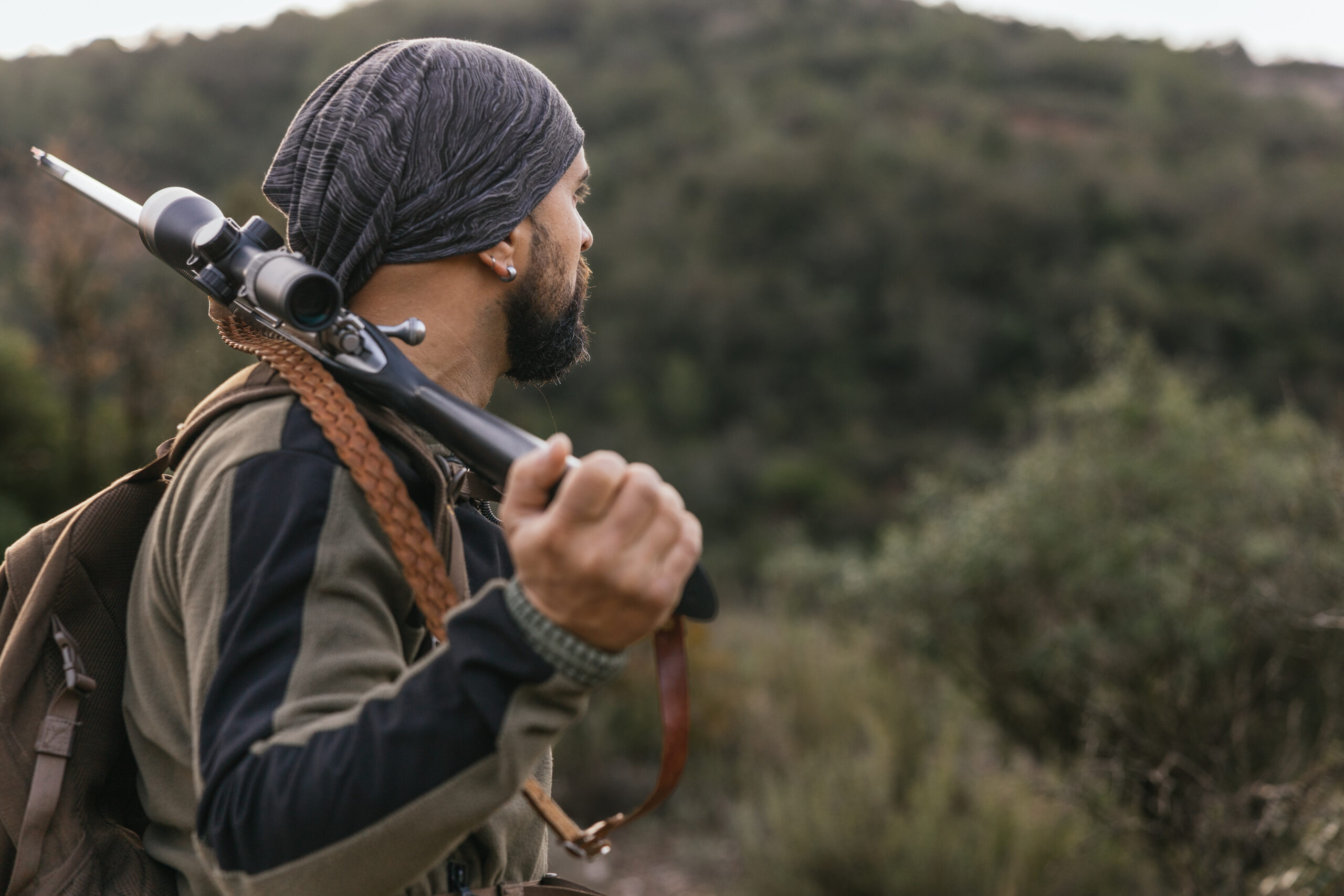 Hunter carrying a rifle through the forest during spring turkey hunting season, representing Black outdoor traditions and hunting heritage.