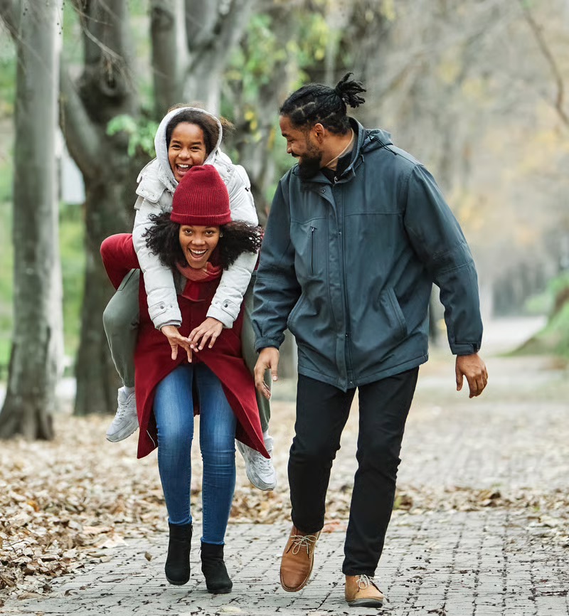 Black family enjoying a walk together outdoors during the fall season.